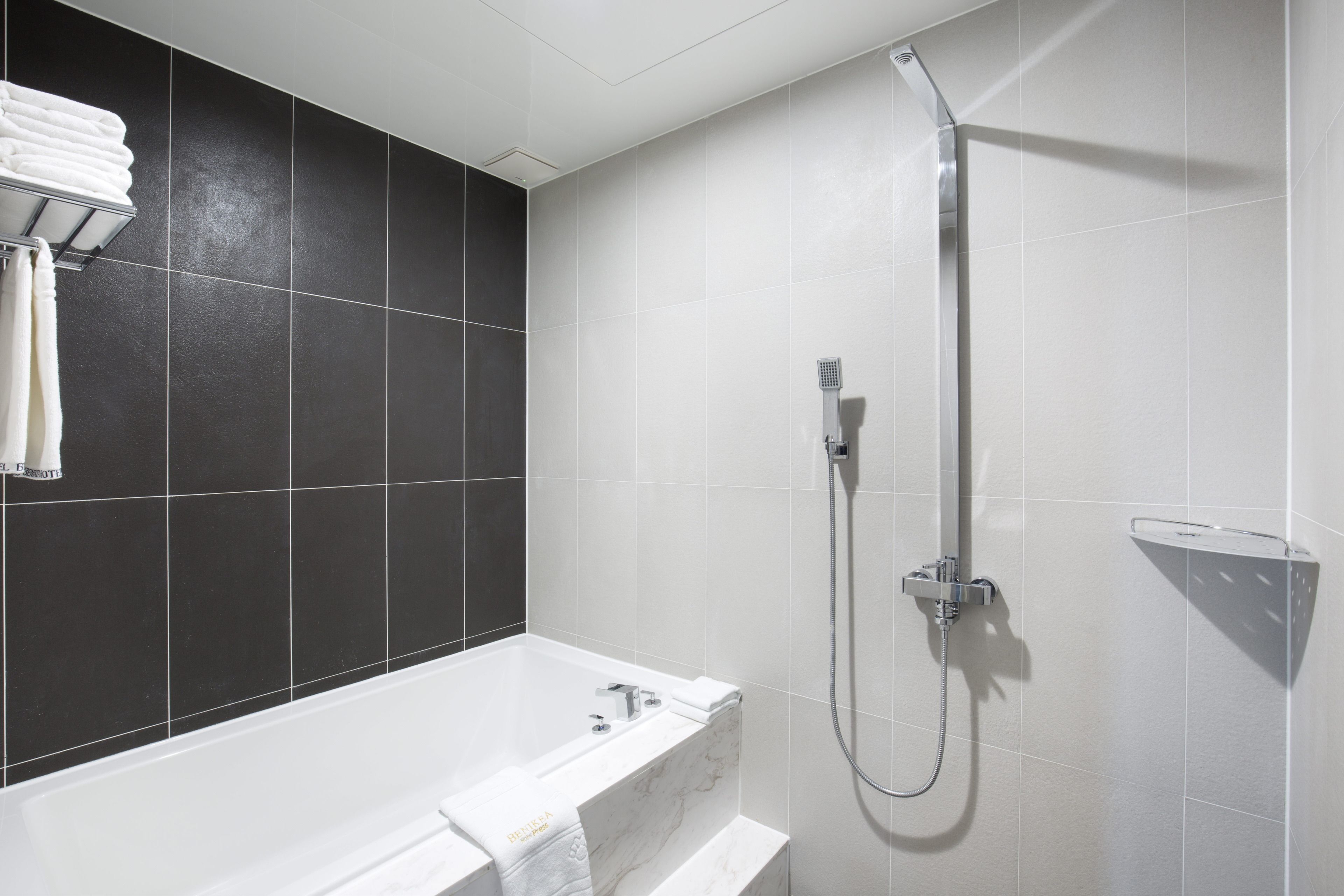A modern bathroom with a bathtub, a shower, and a towel rack.