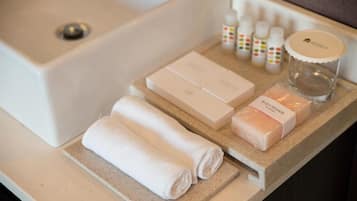 Una encimera de baño con artículos de aseo, incluyendo una esponja de cuerpo, toallas y botellas de jabón.