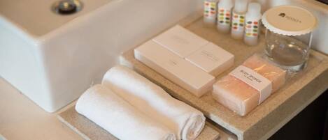 Una encimera de baño con artículos de aseo, incluyendo una esponja de cuerpo, toallas y botellas de jabón.