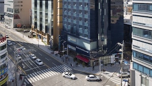 A modern hotel with a prominent glass facade, located in a busy urban area with other high-rise buildings. - Benikea Hotel Haeundae (Busan)