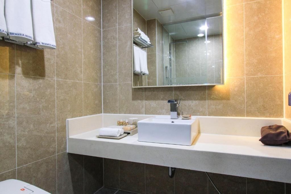 A modern bathroom with a white sink, a mirror, and a towel rack.