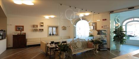 A modern interior with a wooden floor, a white sofa, a decorative bench, and a large potted plant.
