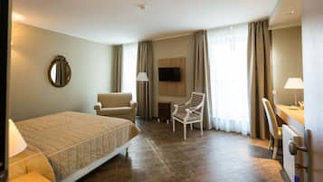 Relax in a spacious room with a large bed, chair, desk, and wall-mounted TV.