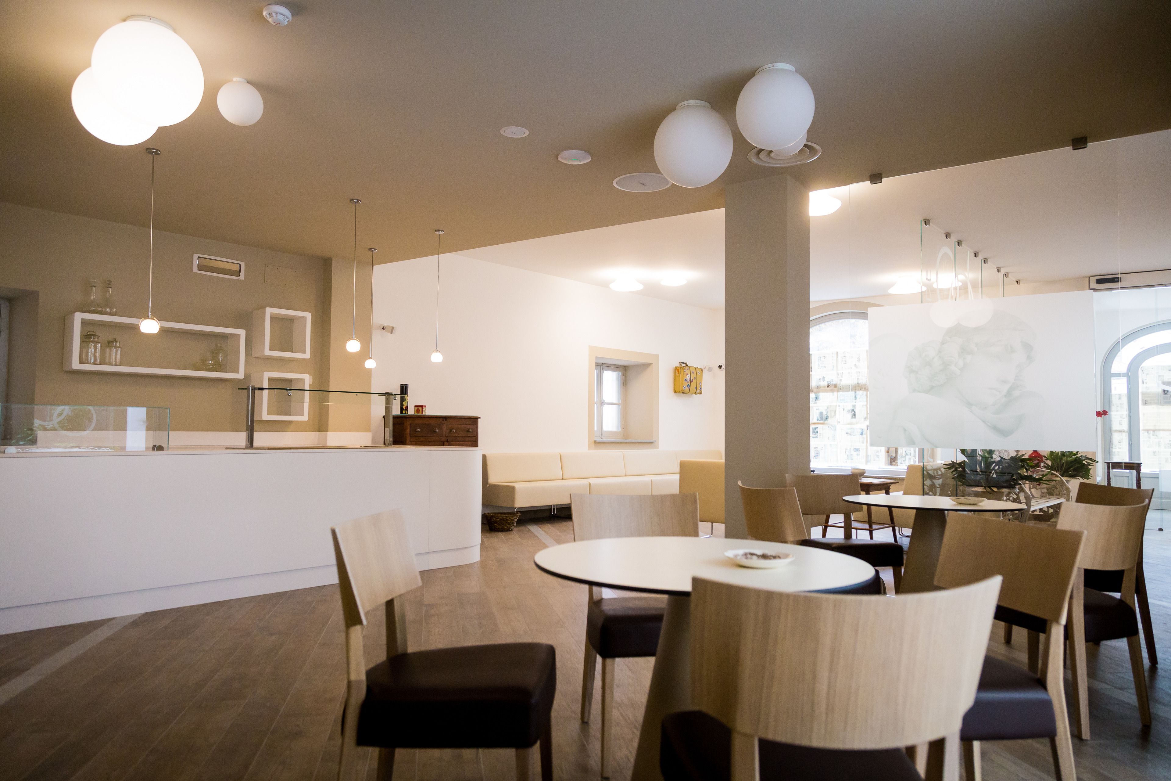 Un interior de restaurante moderno con mesas redondas, sillas de madera e iluminación colgante.