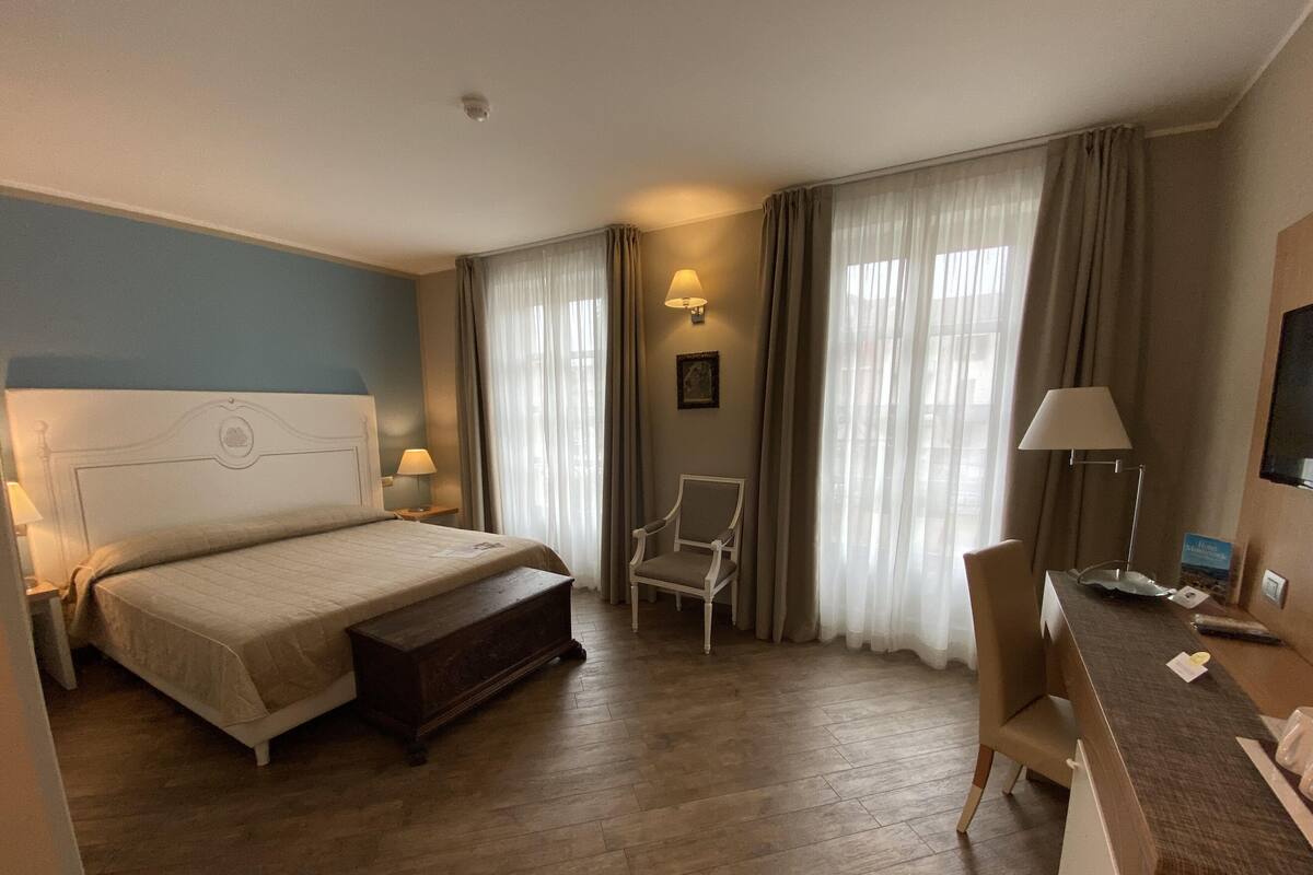 A hotel room with a bed, a chair, a desk, and a television.
