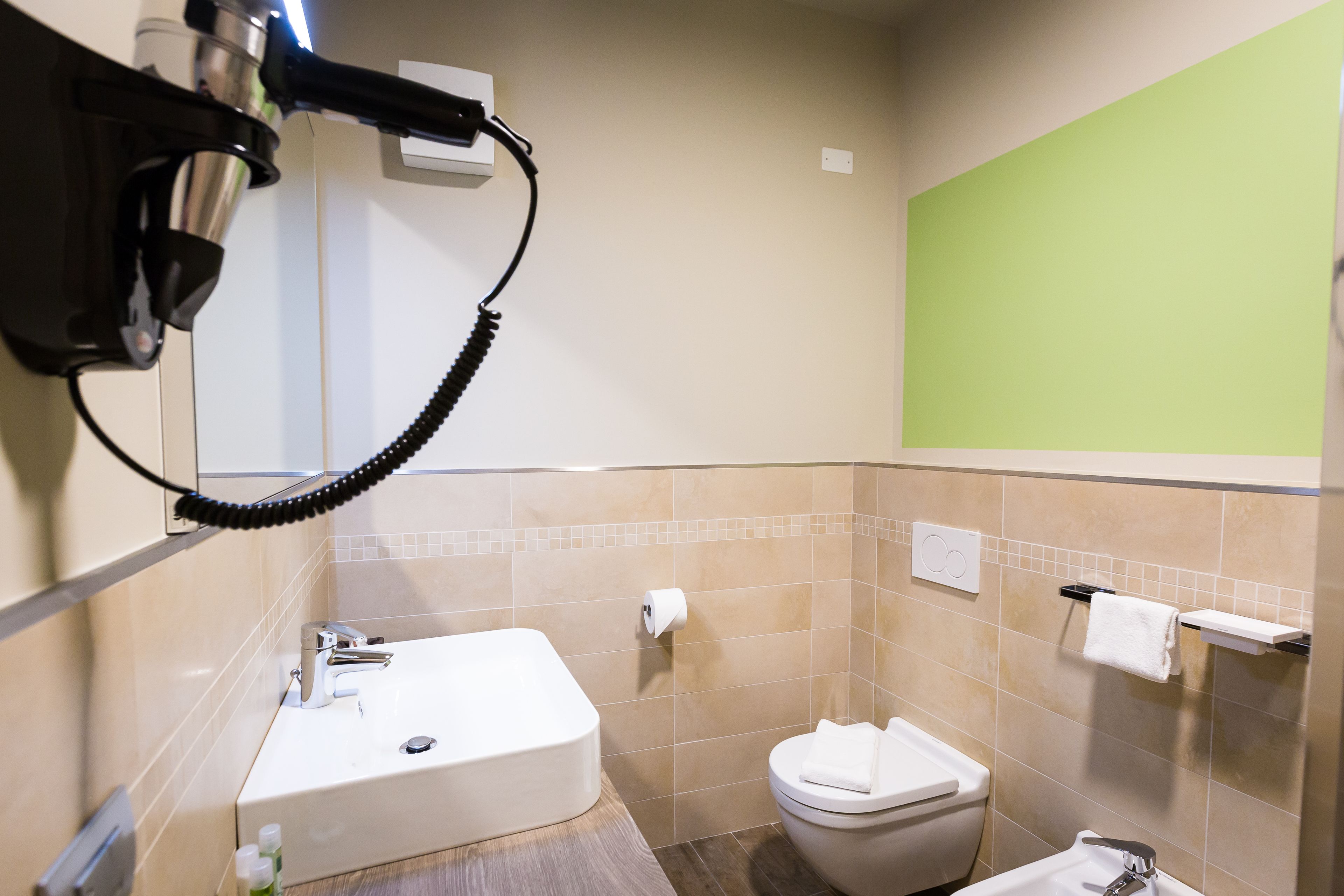Un baño con lavamanos, inodoro y perchero para toallas.