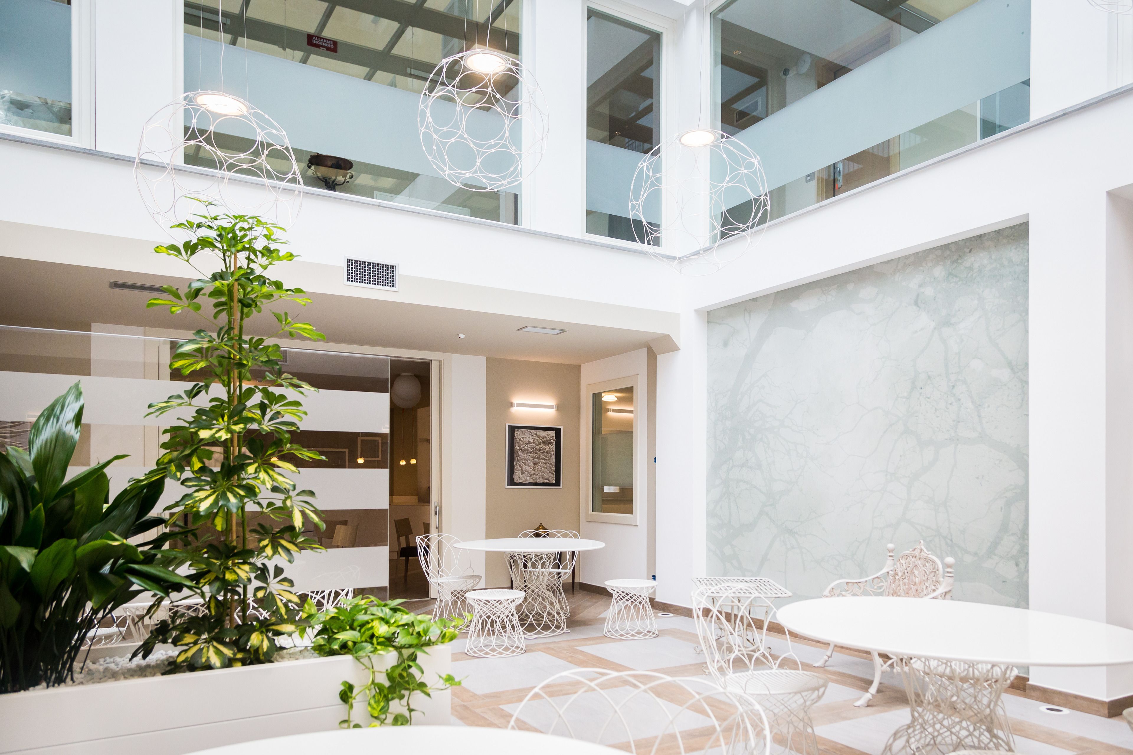 A spacious indoor area with a high ceiling, multiple seating arrangements, and a large plant.