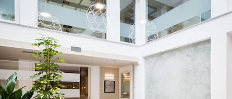 A spacious indoor area with a high ceiling, multiple seating arrangements, and a large plant.