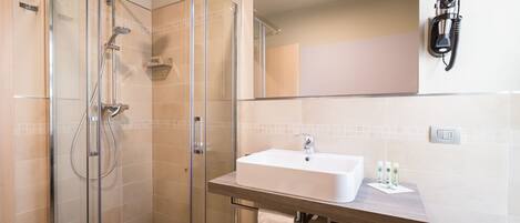 A modern bathroom with a glass-enclosed shower, a white sink, and a mirror above it.
