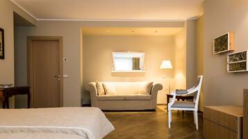 A hotel room with a bed, a sofa, a chair, a desk, and a wardrobe.
