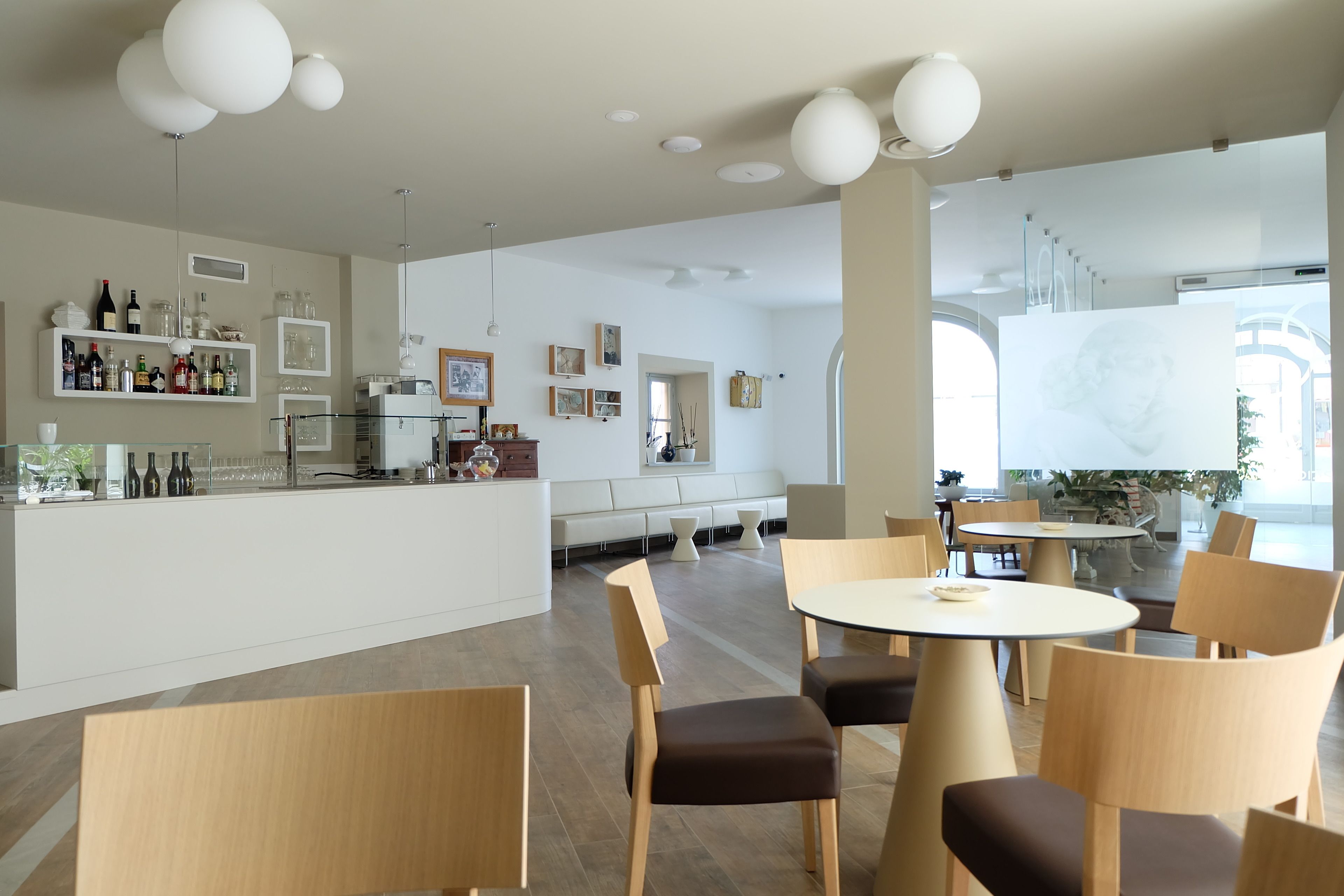 A modern restaurant with a bar area, seating arrangements, and a large window providing natural light.