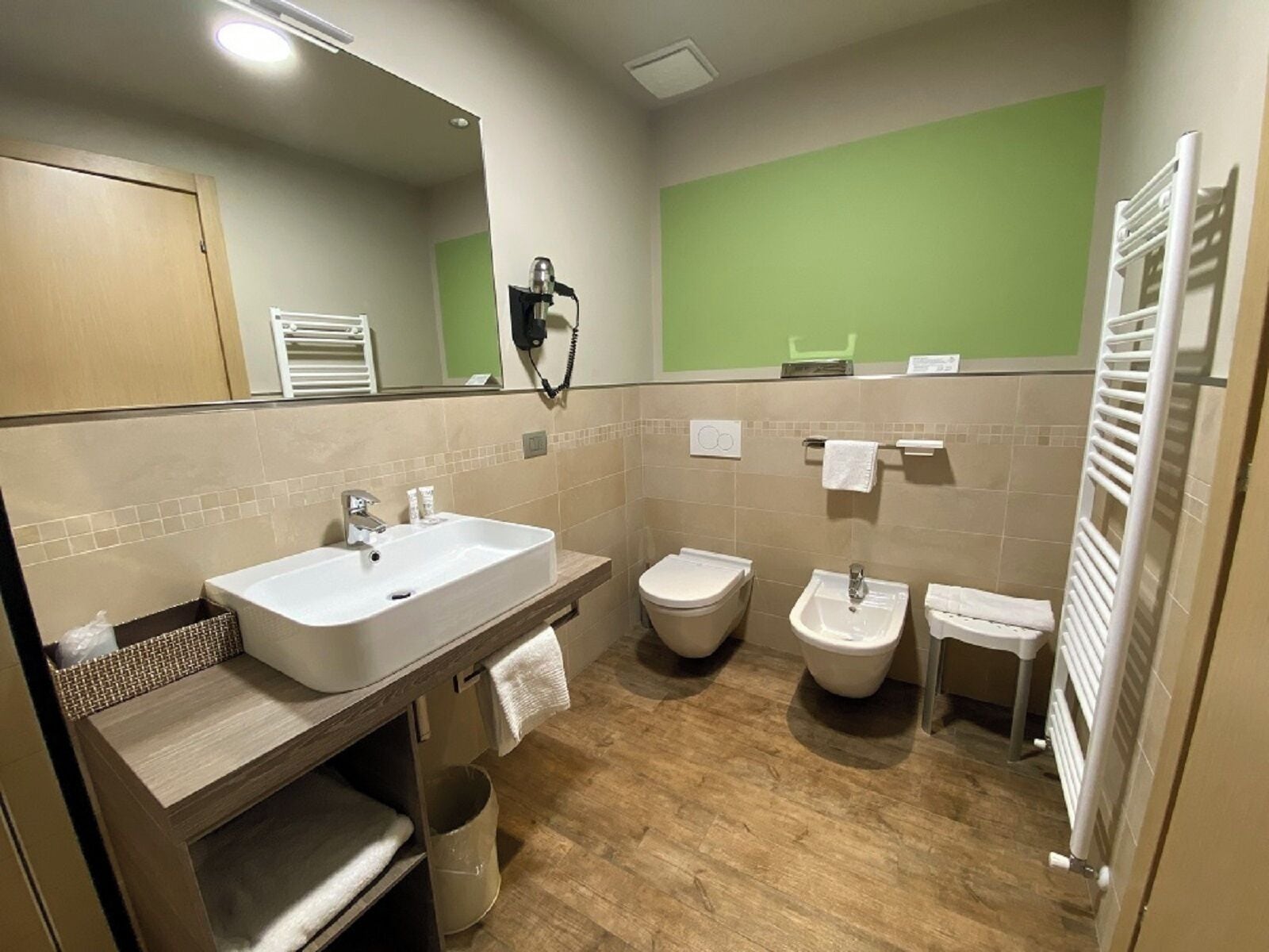 A modern bathroom with a large sink, toilet, bidet, and a towel rack.