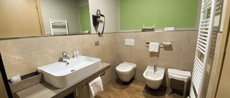 A modern bathroom with a large sink, toilet, bidet, and a towel rack.
