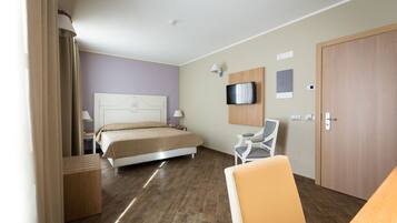 Habitación de hotel con cama, televisor montado en la pared, escritorio y una silla.
