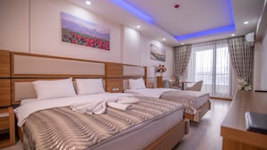 A hotel room with two beds, a desk, and a window with curtains.