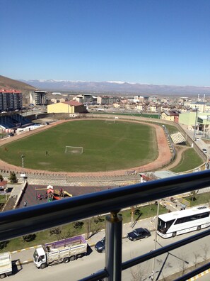 A stadium with a large field, seating areas, and a view of mountains in the background.