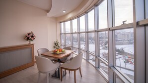A dining area with a table set for two, a decorative vase, and a view of a snowy landscape through large windows.