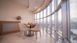 A modern dining area with a table and chairs, a decorative vase, and large windows offering a city view.