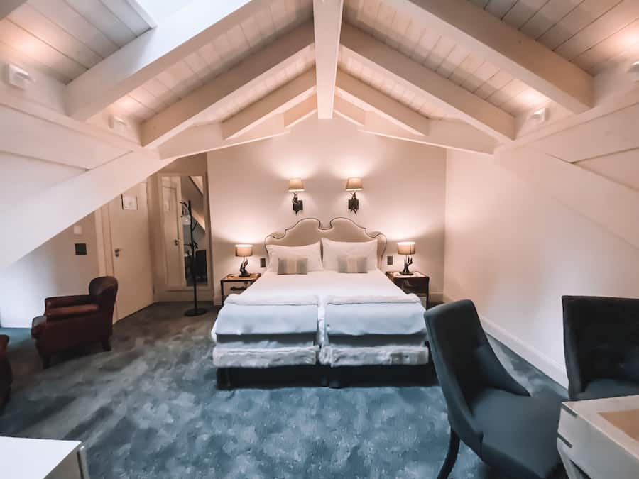 A bedroom with a large bed, two bedside tables with lamps, a chair, and a small table.