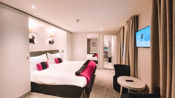 A hotel room with a large bed, a desk, and a television.