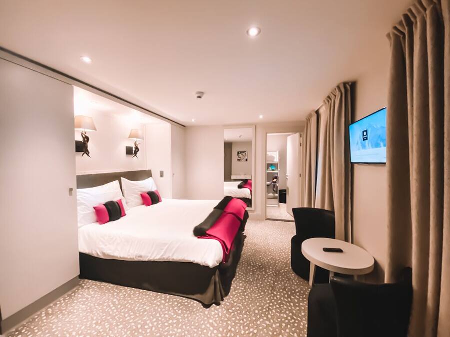 A hotel room with a large bed, a desk, and a television.
