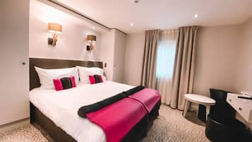 Una habitación de hotel con una cama grande, lámparas de noche, una mesita redonda y una silla.
