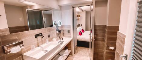 A modern bathroom with dual sinks, a large mirror, and a shower area.