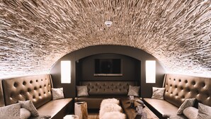 Un espace salon accueillant doté d’un plafond incurvé, de sièges confortables et d’une table en bois placée au centre, sur laquelle repose un menu.