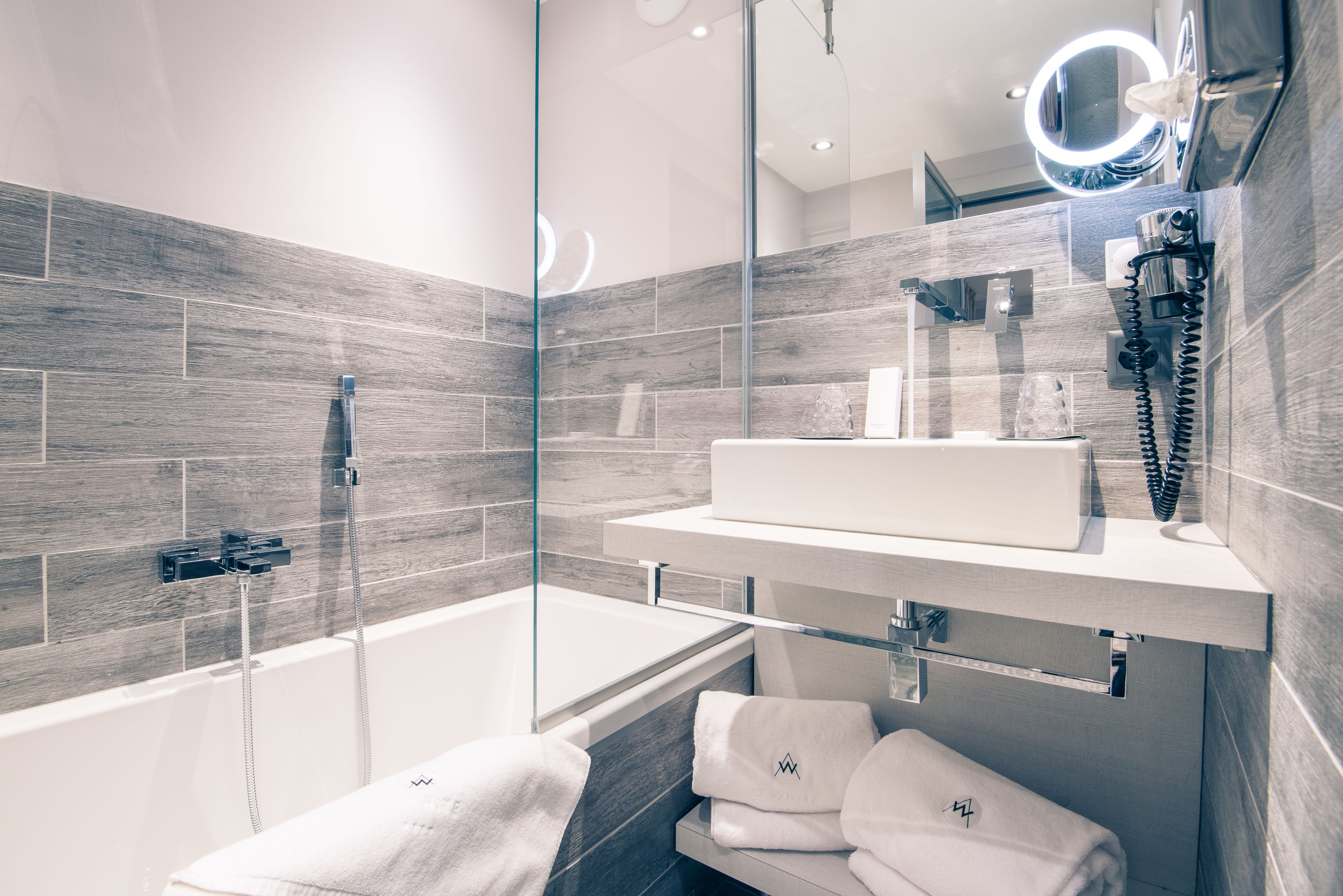 A modern bathroom with a glass-enclosed shower, a built-in sink, and a vanity with a mirror.