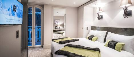 A hotel room with a large bed, a television mounted on the wall, and a door leading to a bathroom.