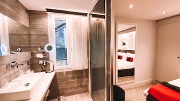 A modern hotel bathroom with a large mirror, a sink, and a shower area.