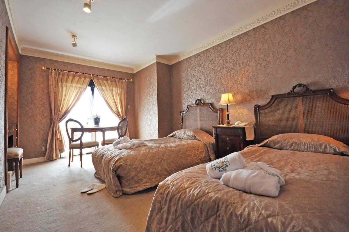 Een hotelkamer met twee bedden, een tafel, een stoel en een lamp.