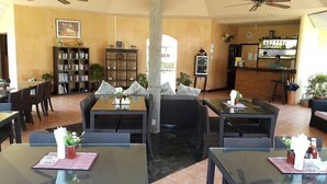 A spacious indoor area with multiple tables and chairs, a bar area, and a large bookshelf. - Palm Garden Resort Khaolak (Takua Pa)