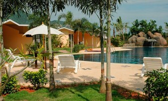 A pool area with lounge chairs, umbrellas, and a waterfall feature.