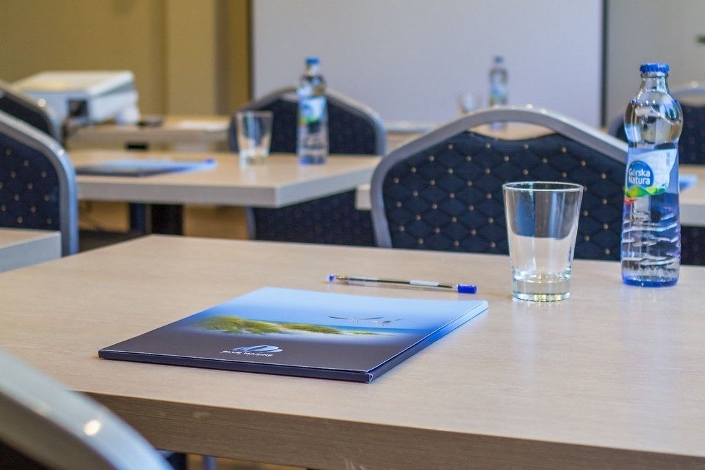 A conference room with a laptop, a glass of water, and a bottle of water on the table.