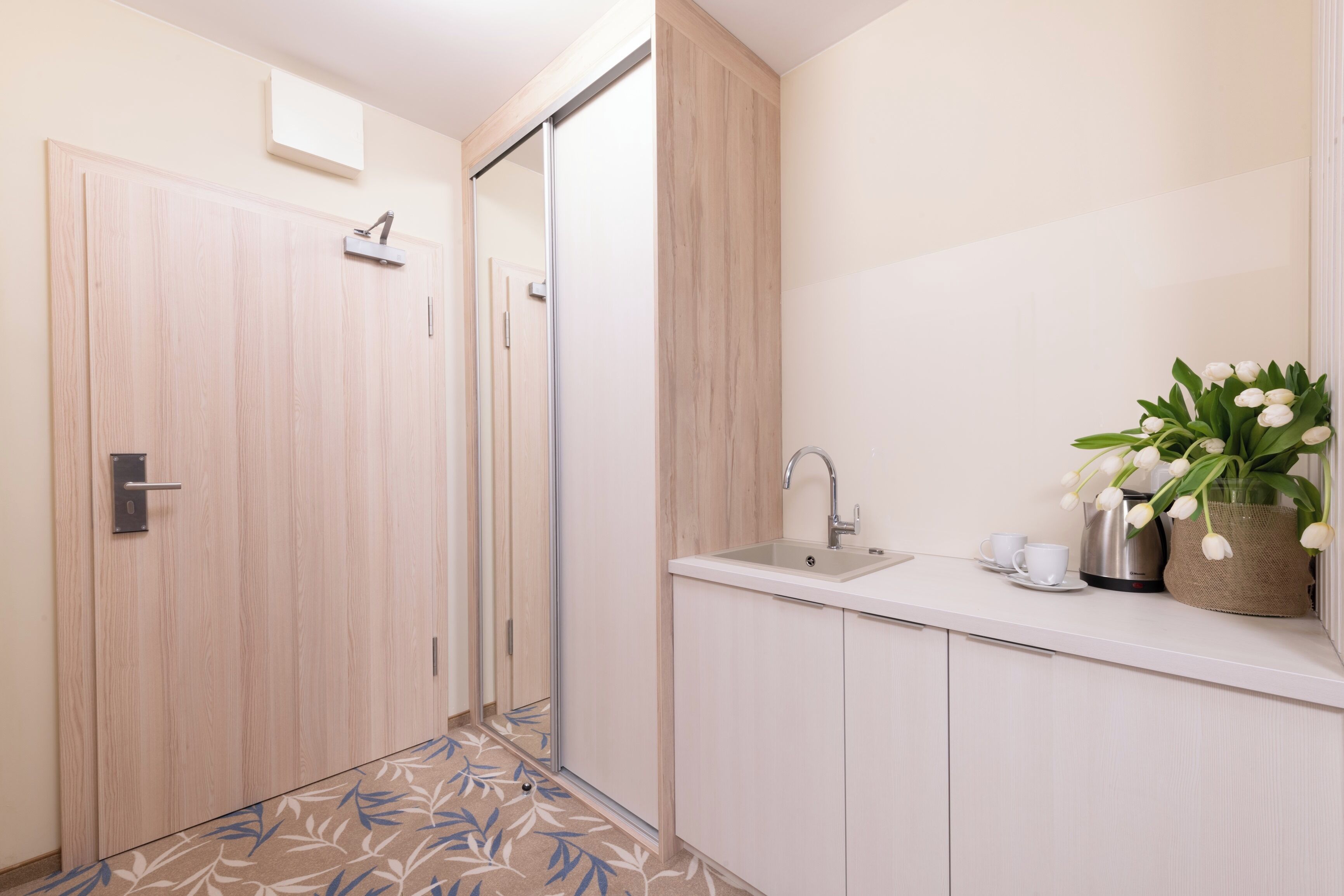 Een moderne badkamer met een houten deur, een wastafel en een spiegel.