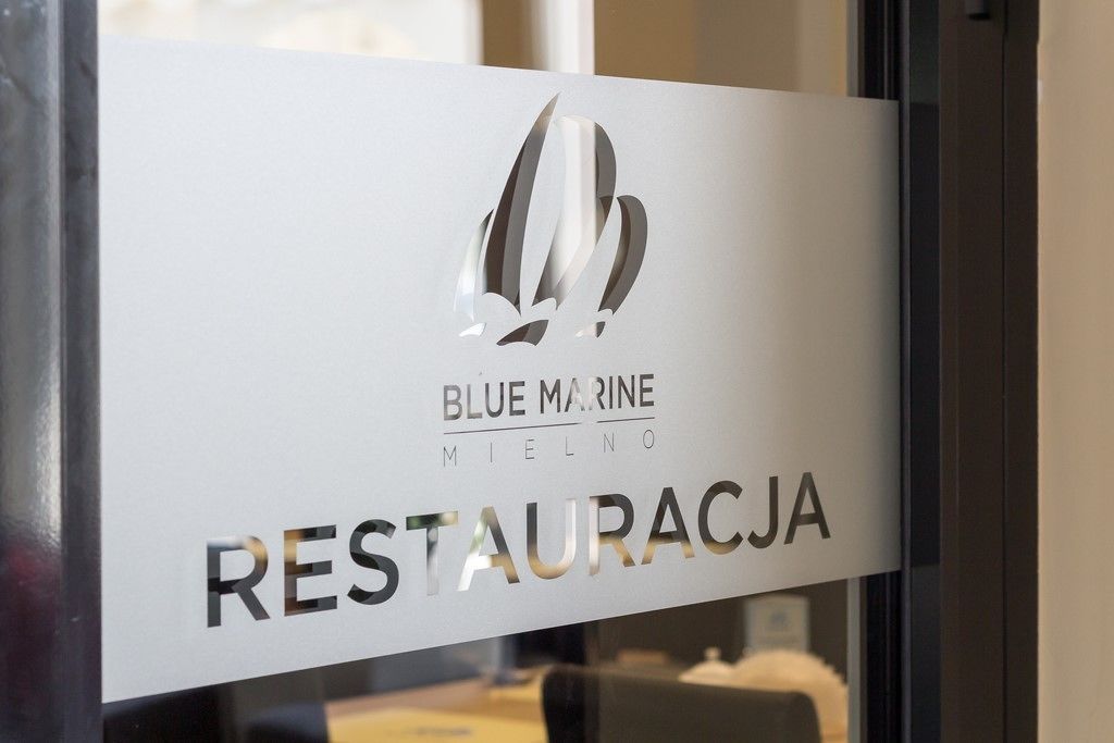 A sign with the text "BLUE MARINE MIELNO RESTAURACJA" and a logo.