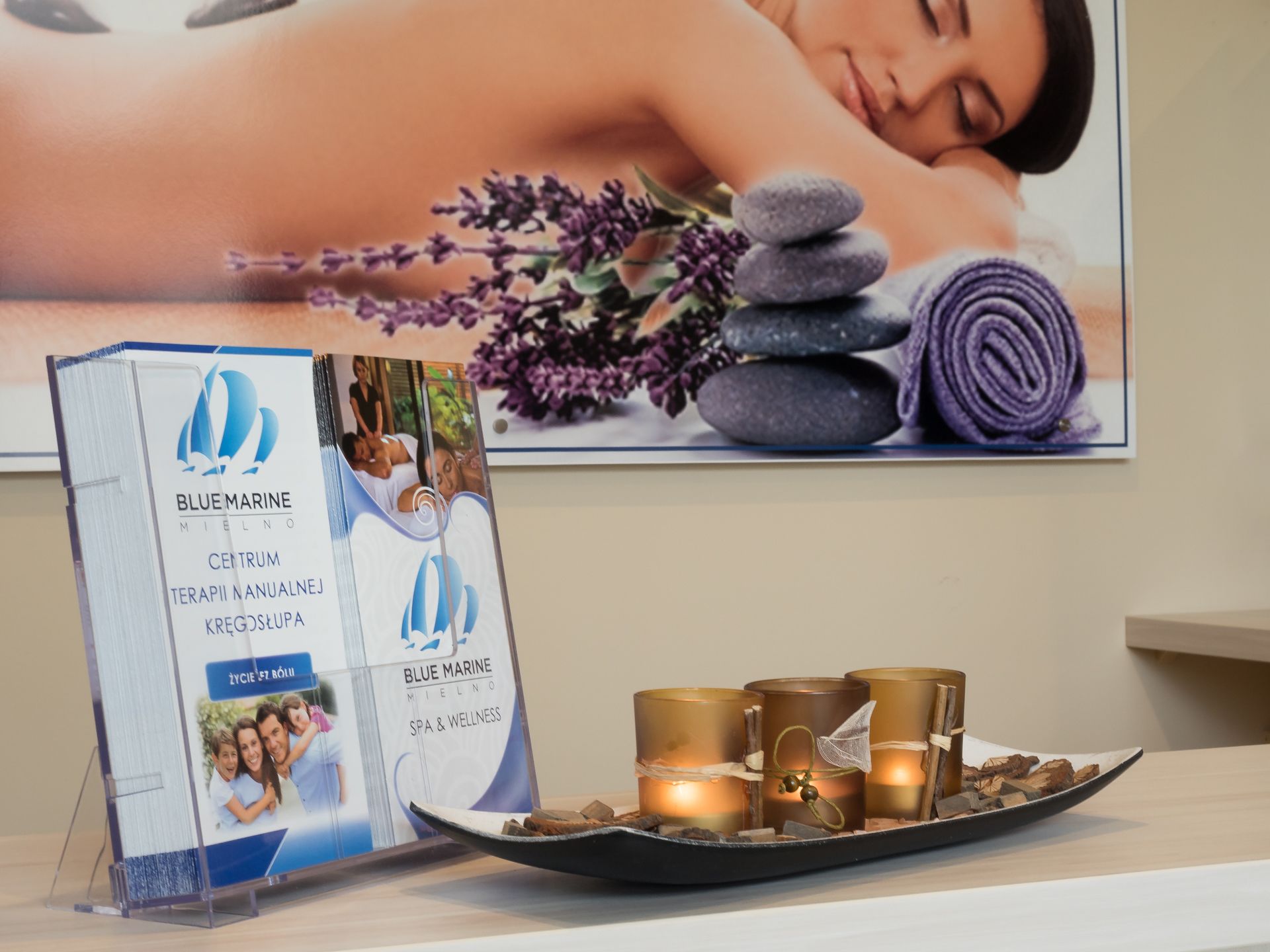 A brochure stand with a spa advertisement, a tray with candles, and a stone arrangement.