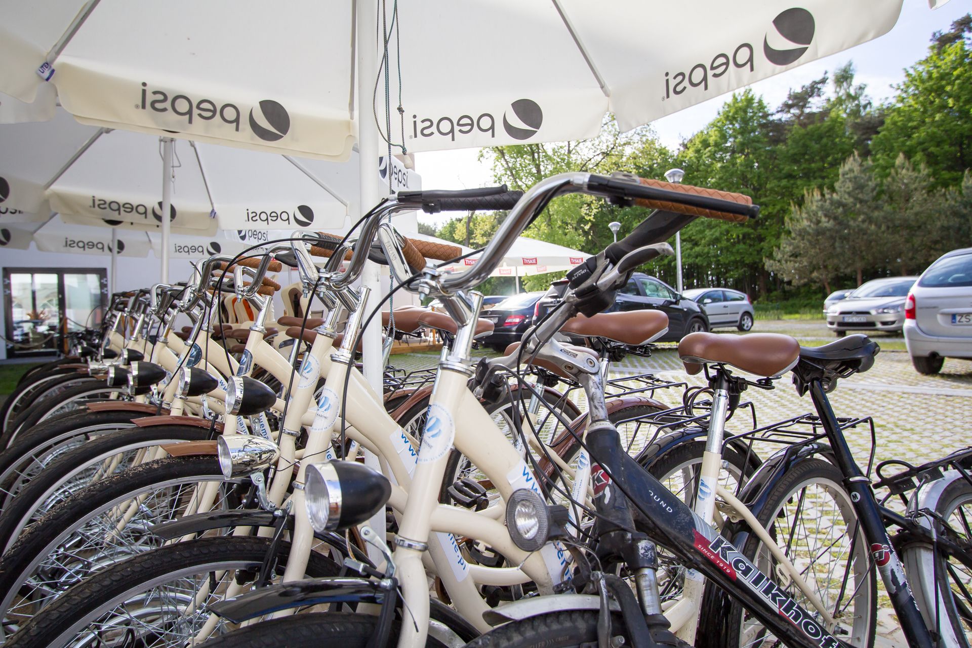 Una fila di biciclette parcheggiate sotto ombrelloni con la pubblicità di Pepsi.