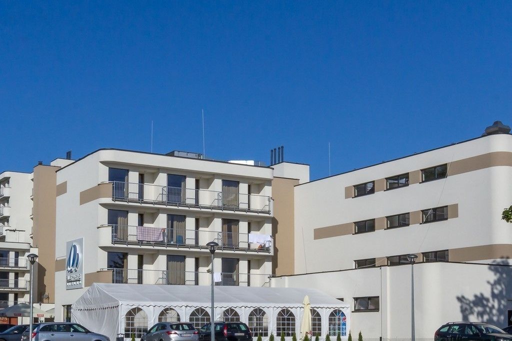 A multi-story hotel with balconies, a spa sign, and a tented area.