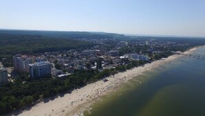 An aerial view of a coastal city with a beach, buildings, and a bridge. - Aparthotel Miedzyzdroje (Miedzyzdroje)