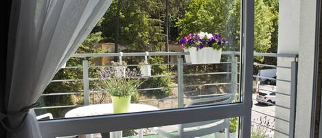 A balcony with white chairs, a small table, and potted plants.