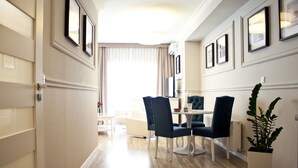 A hotel room with a dining area featuring a table, chairs, and a potted plant. - Aparthotel Miedzyzdroje (Miedzyzdroje)