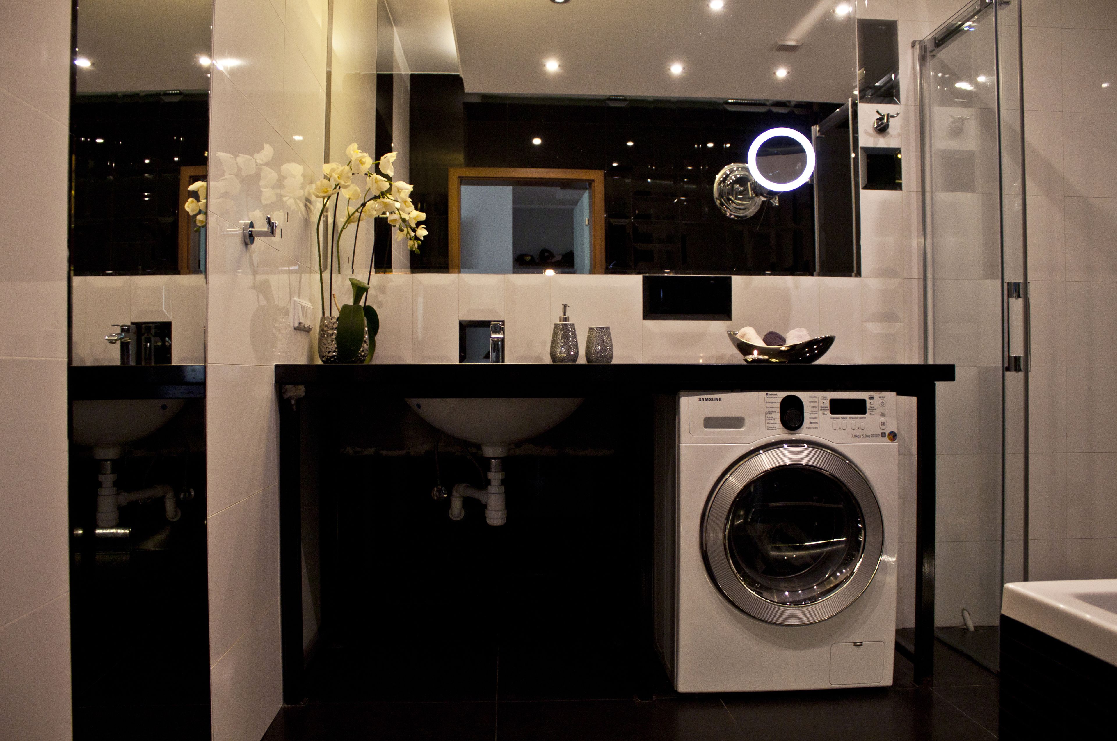 Un baño moderno con lavadora integrada, lavamanos y espejo.