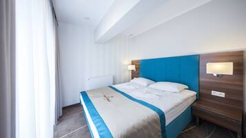 Una habitación de hotel moderna con una cama grande, cabecera de madera y una mesita de noche con lámpara.