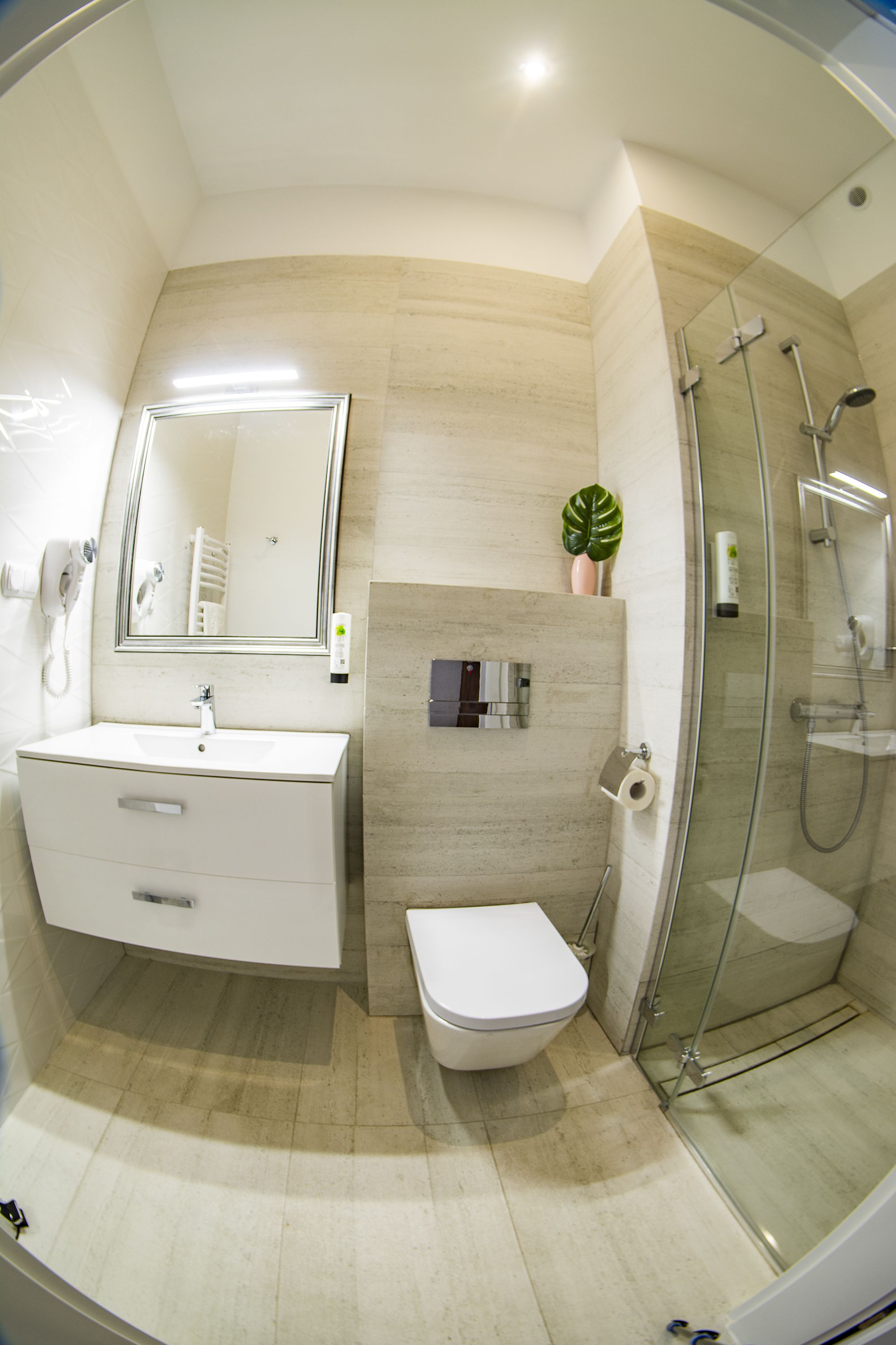 A modern bathroom with a glass-enclosed shower, a white sink, and a toilet.