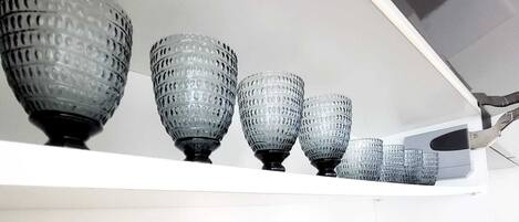A kitchen with a white countertop displaying various glassware and plates.