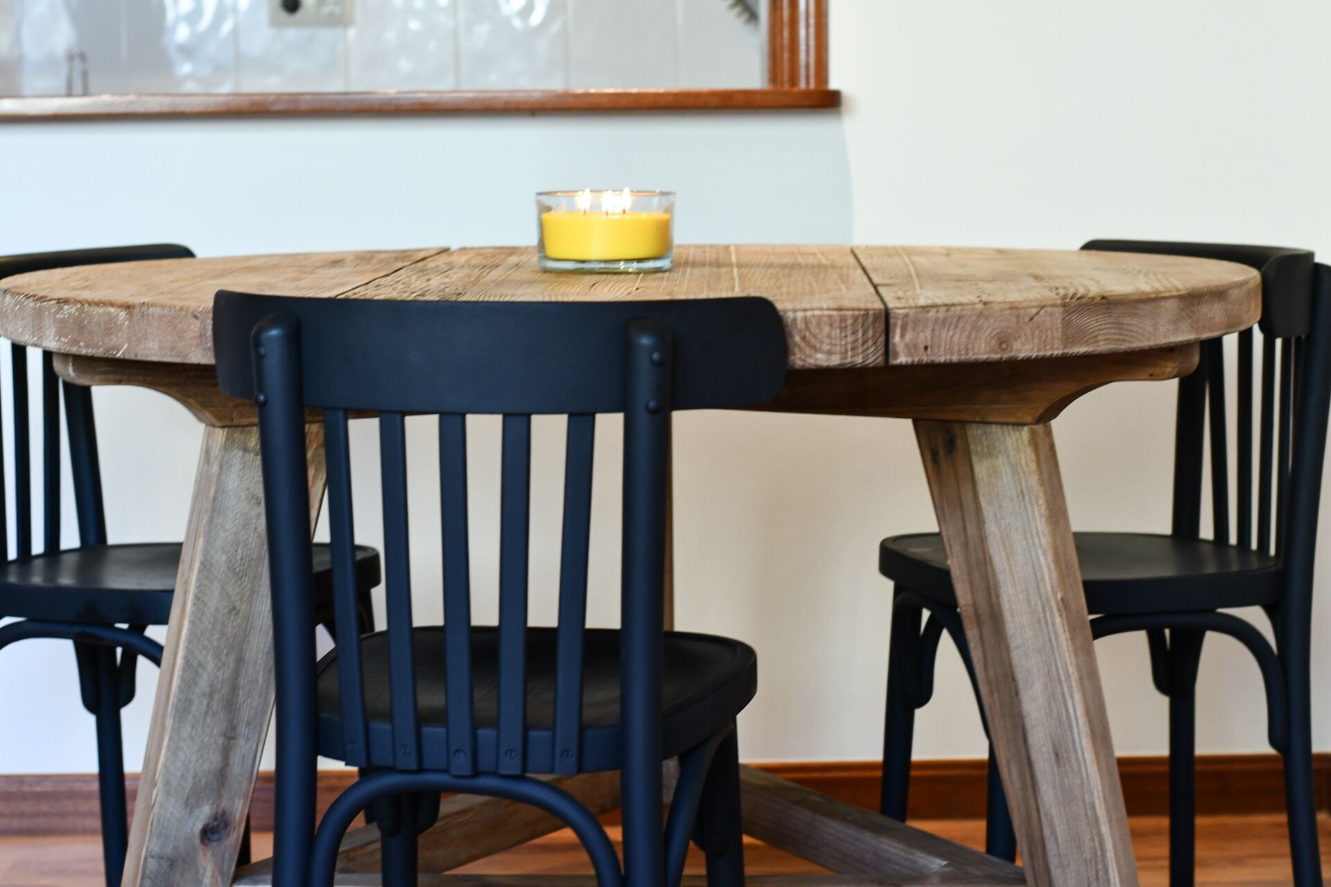 Una mesa redonda de madera con una vela en un candelabro de vidrio.