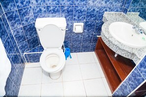 A bathroom with a toilet, a sink, and blue marble tiles. - Hope Gardens Guest House (Nairobi)