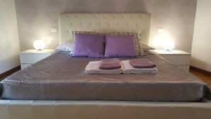 A neatly made bed with a patterned bedspread and two folded towels. - Donizetti Royal (Bergamo)
